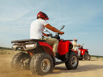 Men in helmets and glasses ride on atv in desert