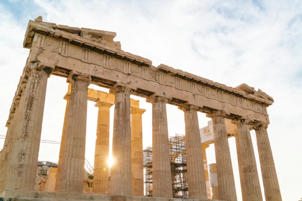 Golden hour sunlight filters through the ancient columns of the Parthenon