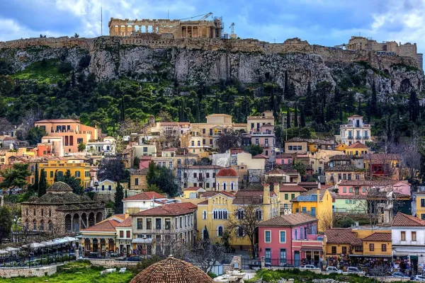 A panoramic view of a Plaka with the ancient Acropolis prominently situated on a rocky hill in the background.