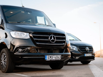Two black Mercedes-Benz vans are parked on a paved surface, one slightly behind the other.